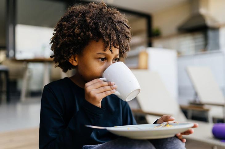 a boy drink a cup of coffee